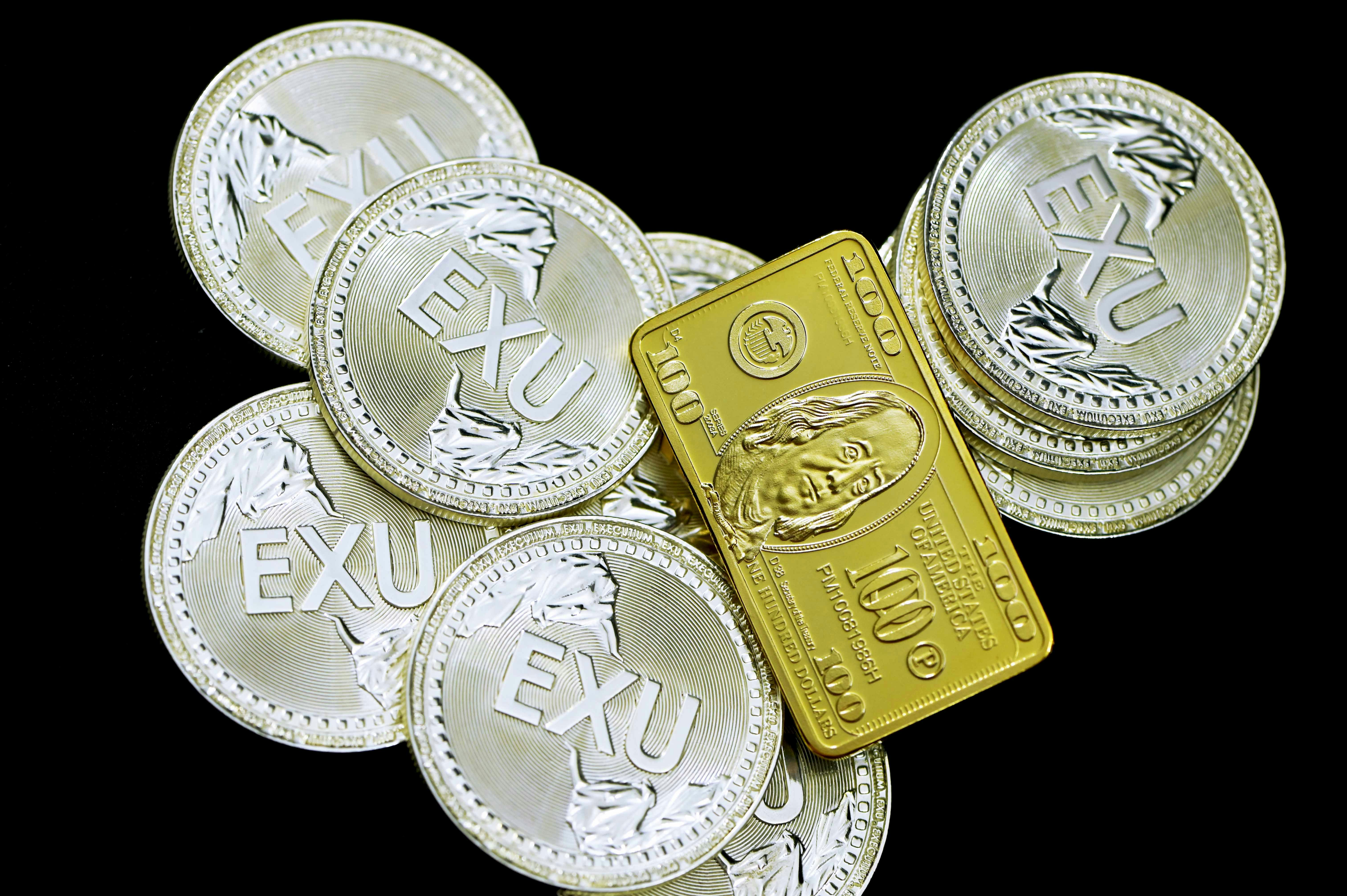 A pile of silver Exu coins with a $100 gold